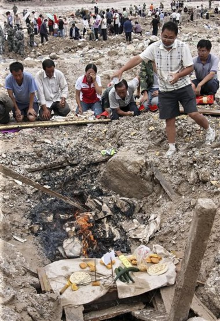 Villagers burn offerings to their relatives who were killed after a mudslide swept through the town of Zhouqu in Gannan prefecture in northwestern China's Gansu province on Thursday, Aug. 12, 2010. Overnight thunderstorms brought new misery to a remote area of northwestern China on Thursday as the death toll from weekend flooding and massive landslides rose to 1,117. The rains triggered new mudslides, leaving five more missing, and another swollen river threatened to overflow.  (AP Photo)**CHINA OUT**